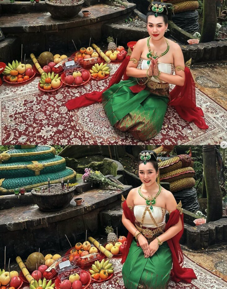 A Thai dancer kneeling with a wai greeting beside fruit offerings, wearing a green silk skirt, red sash and emerald and gold jewellery